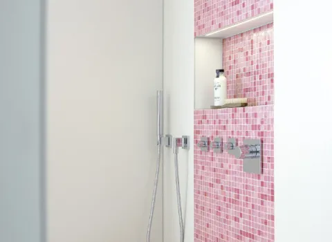 Eine Dusche mit rosa Mosaik-Fliesen und Accessoires.