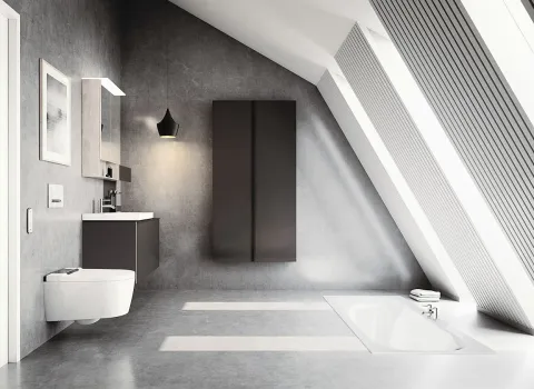 Das lichtduchflutete Badezimmer unter einer Dachschräge ist mit einem Geberit AquaClean Sela-Dusch-WC ausgestattet, das links neben einem schicken Waschtisch platziert ist. 