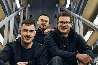 Drei Azubis der b&h concept AG sitzen auf einer Treppe.